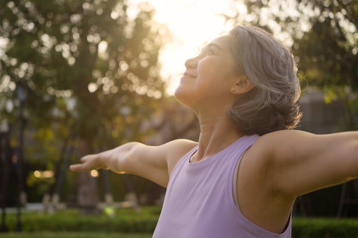 Longevity Ältere Frau, die draussen Yoga übt